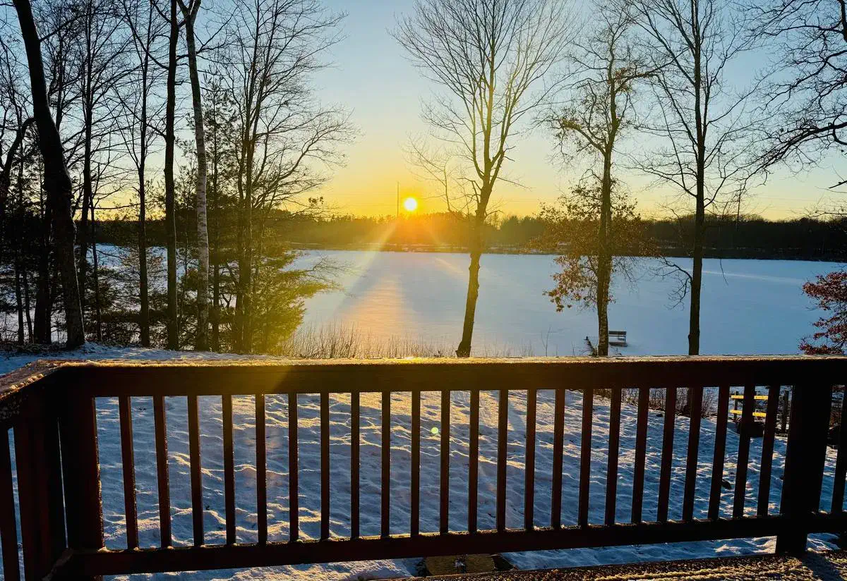 Winter sunset over a frozen lake seen from a cabin deck in Stone Lake, WI