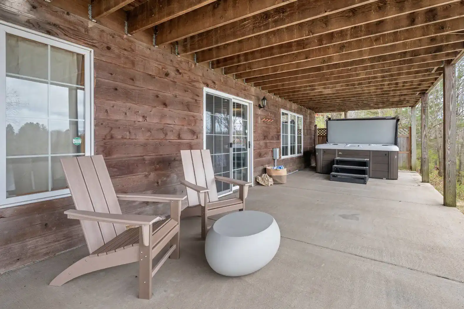 The lower-level veranda is accessible via a short set of stairs on the exterior east side of the home. It features a cozy conversation area and a hot tub.
