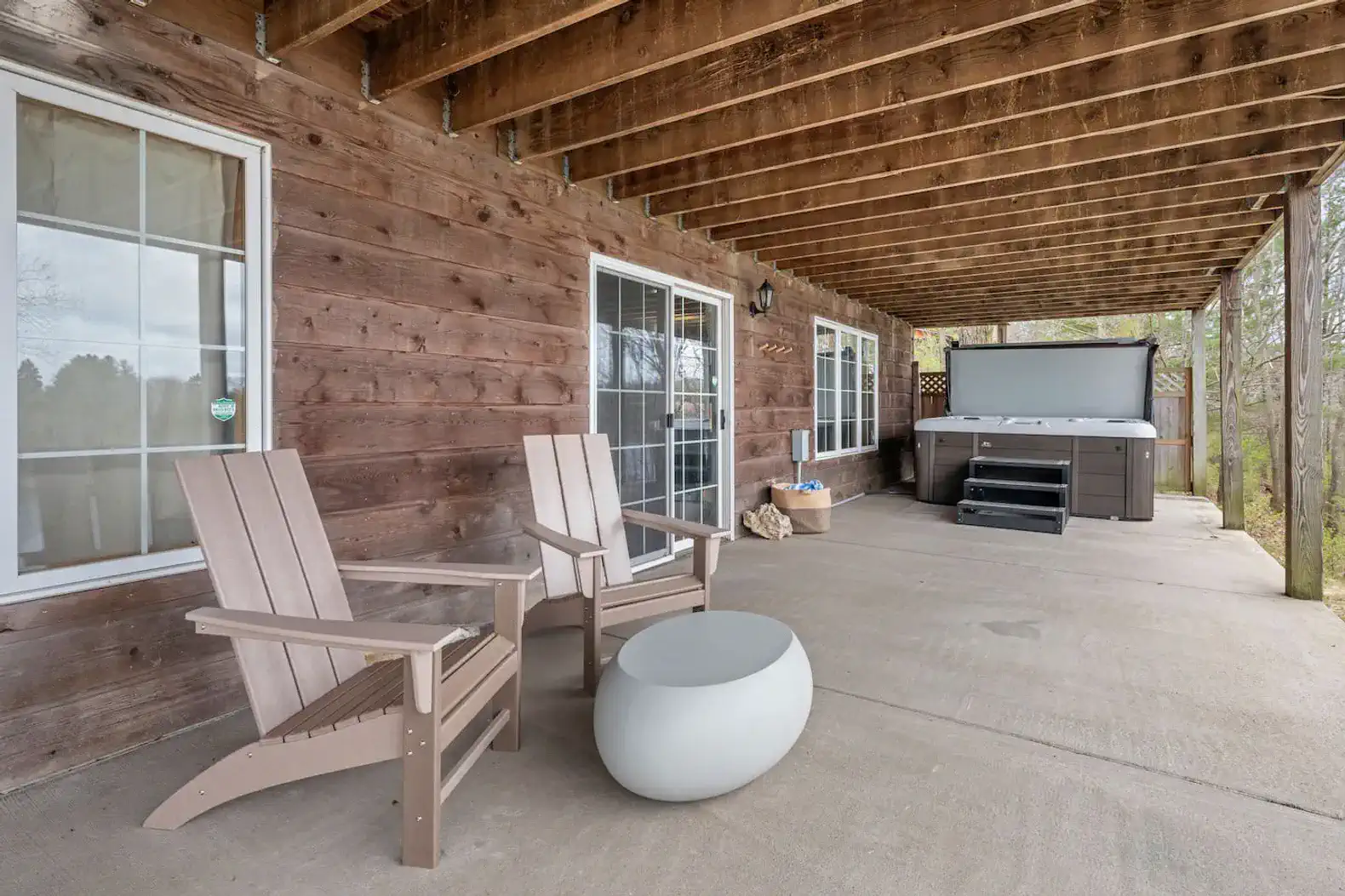 The lower-level veranda is accessible via a short set of stairs on the exterior east side of the home. It features a cozy conversation area and a hot tub.