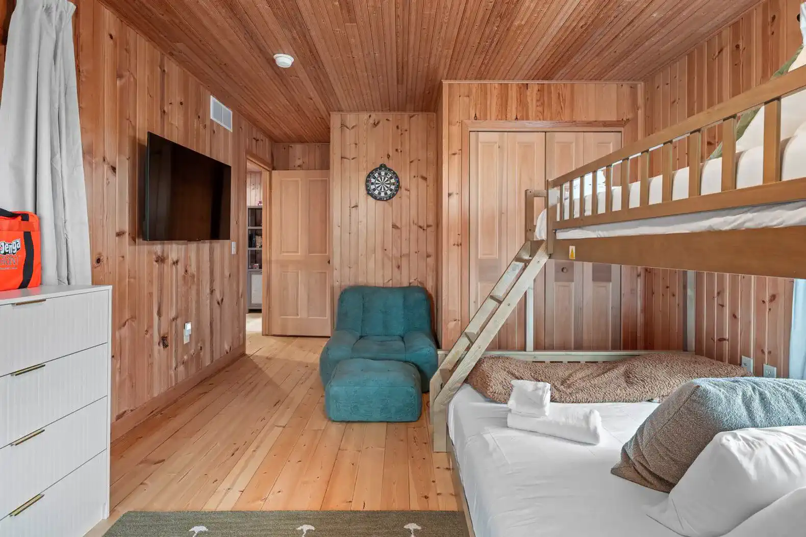 Cozy bunk room with wooden walls, a TV, and a seating area