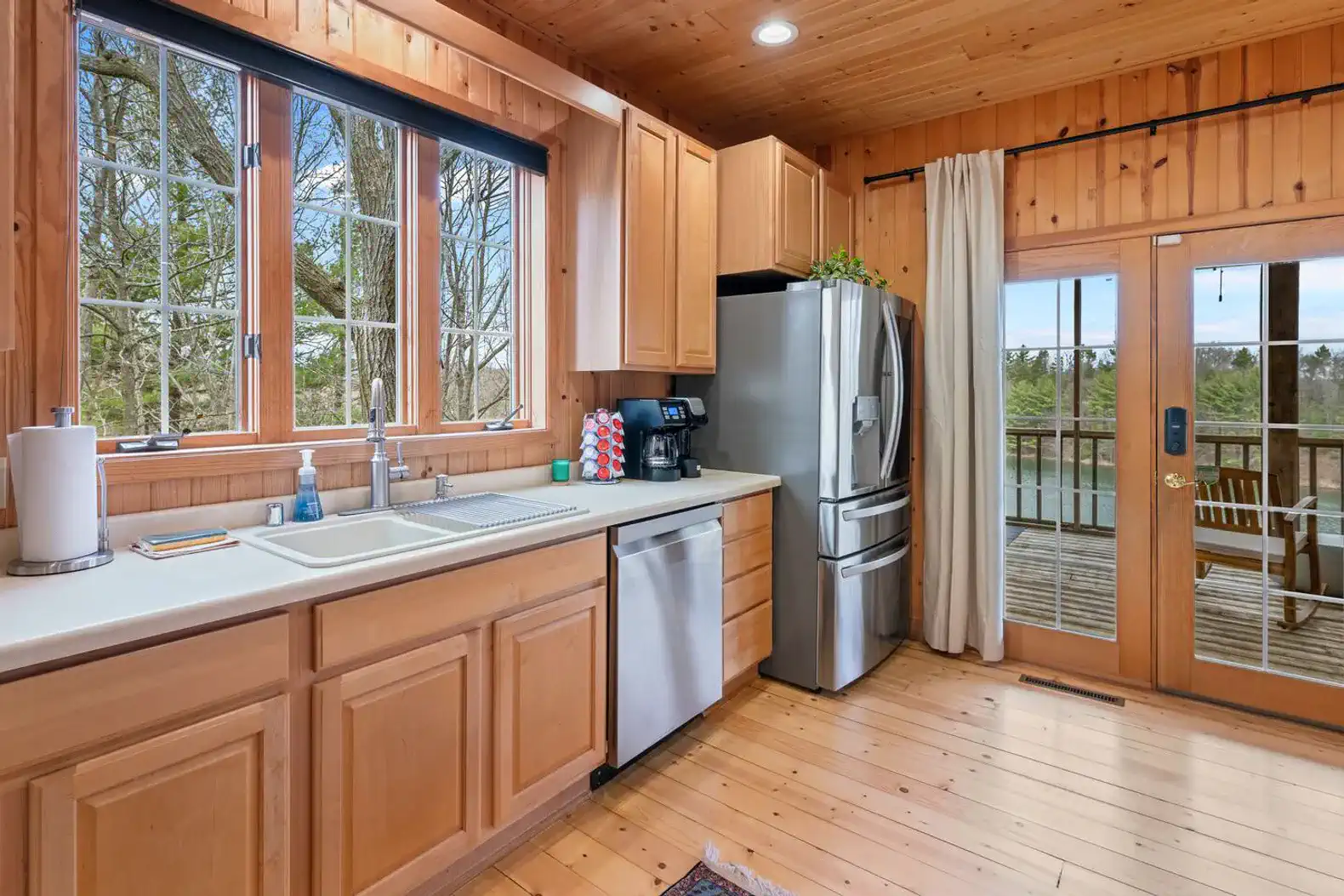 Bright kitchen with wooden cabinets and stainless steel appliances, featuring a view of the outdoor deck