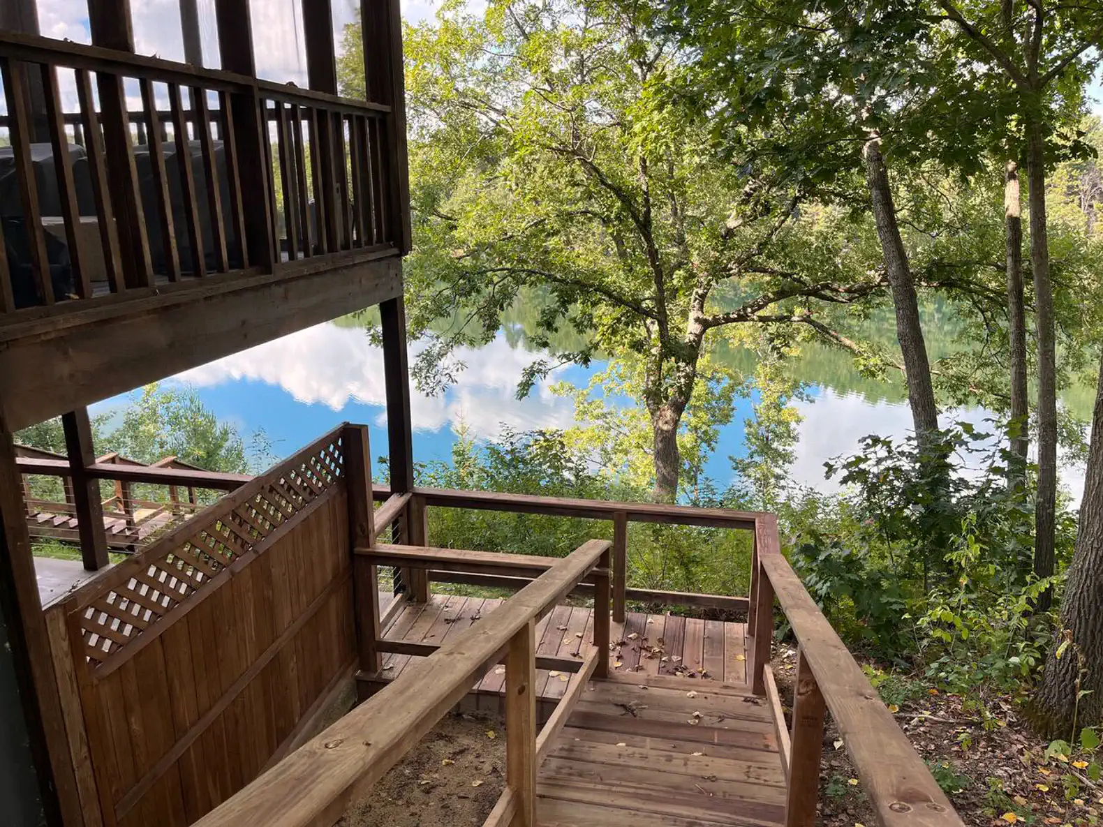 Wooden steps leading down to a serene lake surrounded by trees