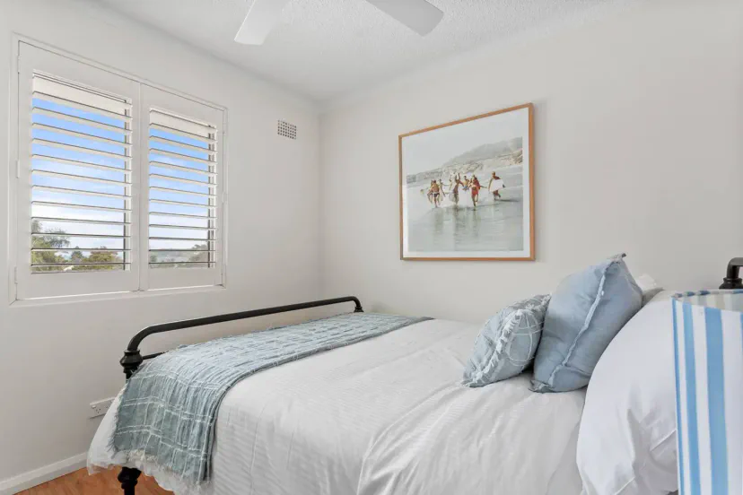 Comfortable Queen bed with wardrobe, ceiling fan and beach glimpses.