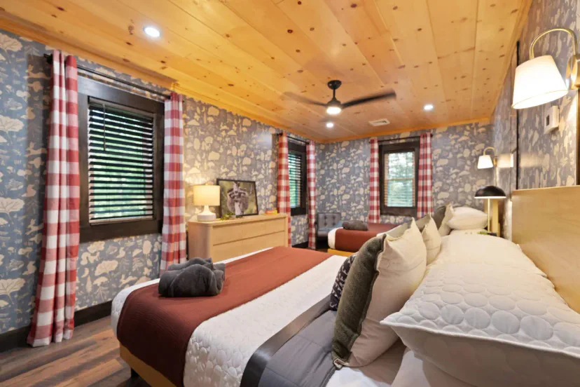 Acogedor dormitorio de invitados con dos camas queen, techo de madera y papel tapiz floral