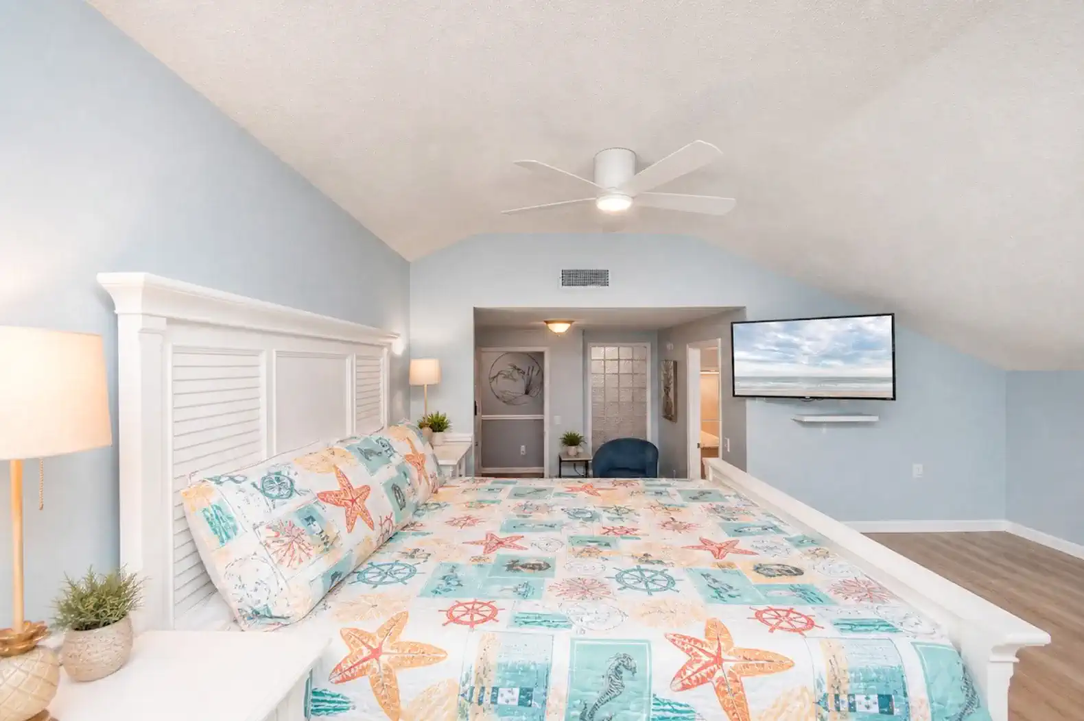 Spacious master bedroom with a large bed, ceiling fan, and beach-themed decor