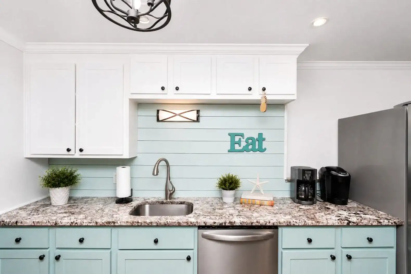 Cozy kitchen with light blue cabinets, granite countertops, and modern appliances