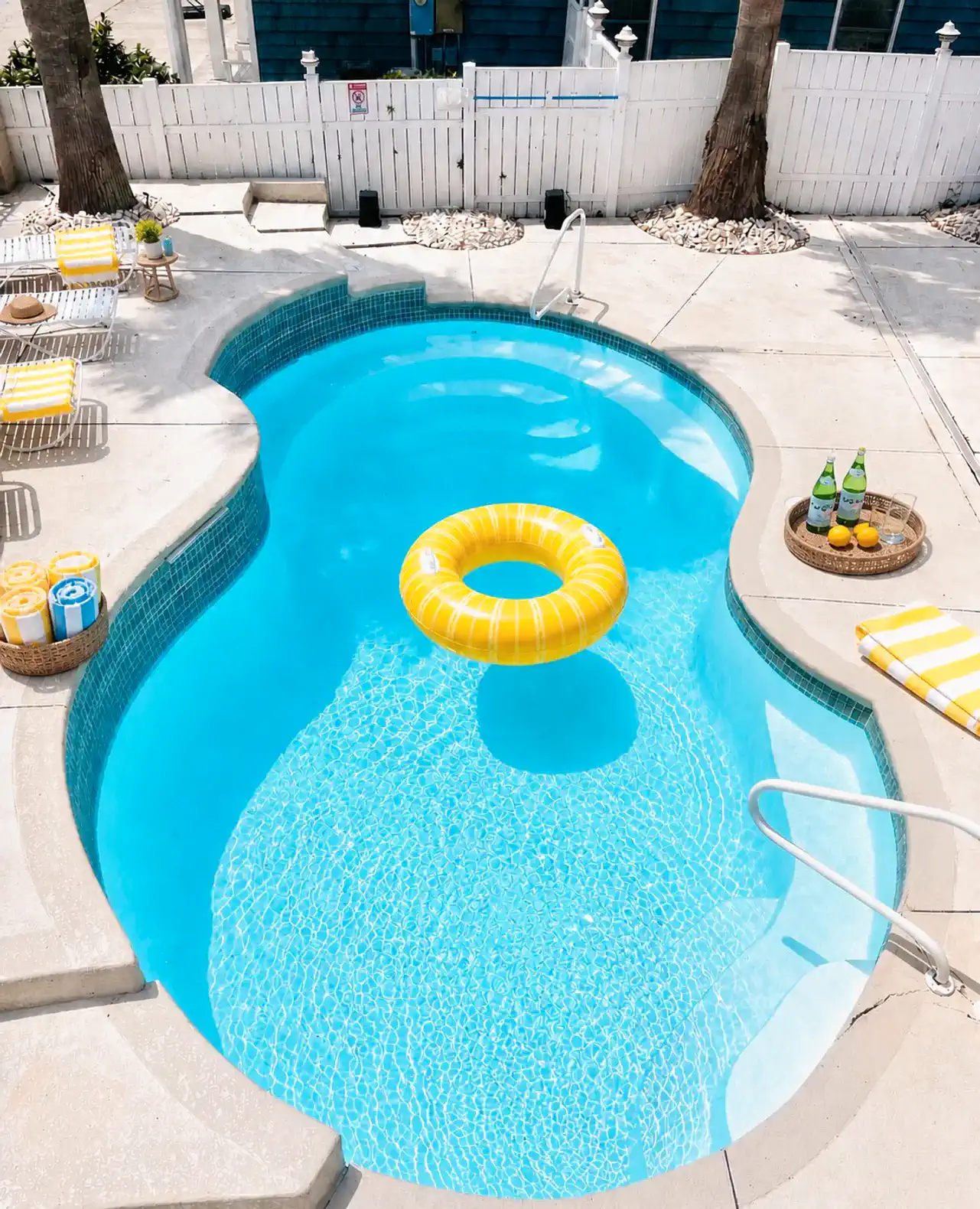 Bright blue pool with a yellow float and lounge chairs nearby