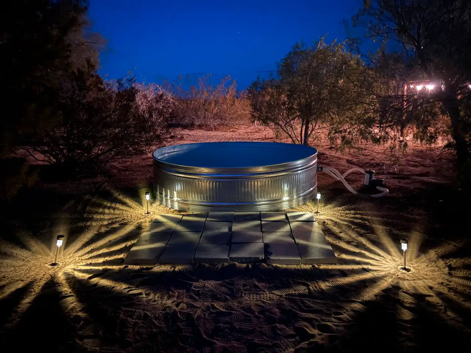 Outdoor hot tub illuminated at night surrounded by desert landscape
