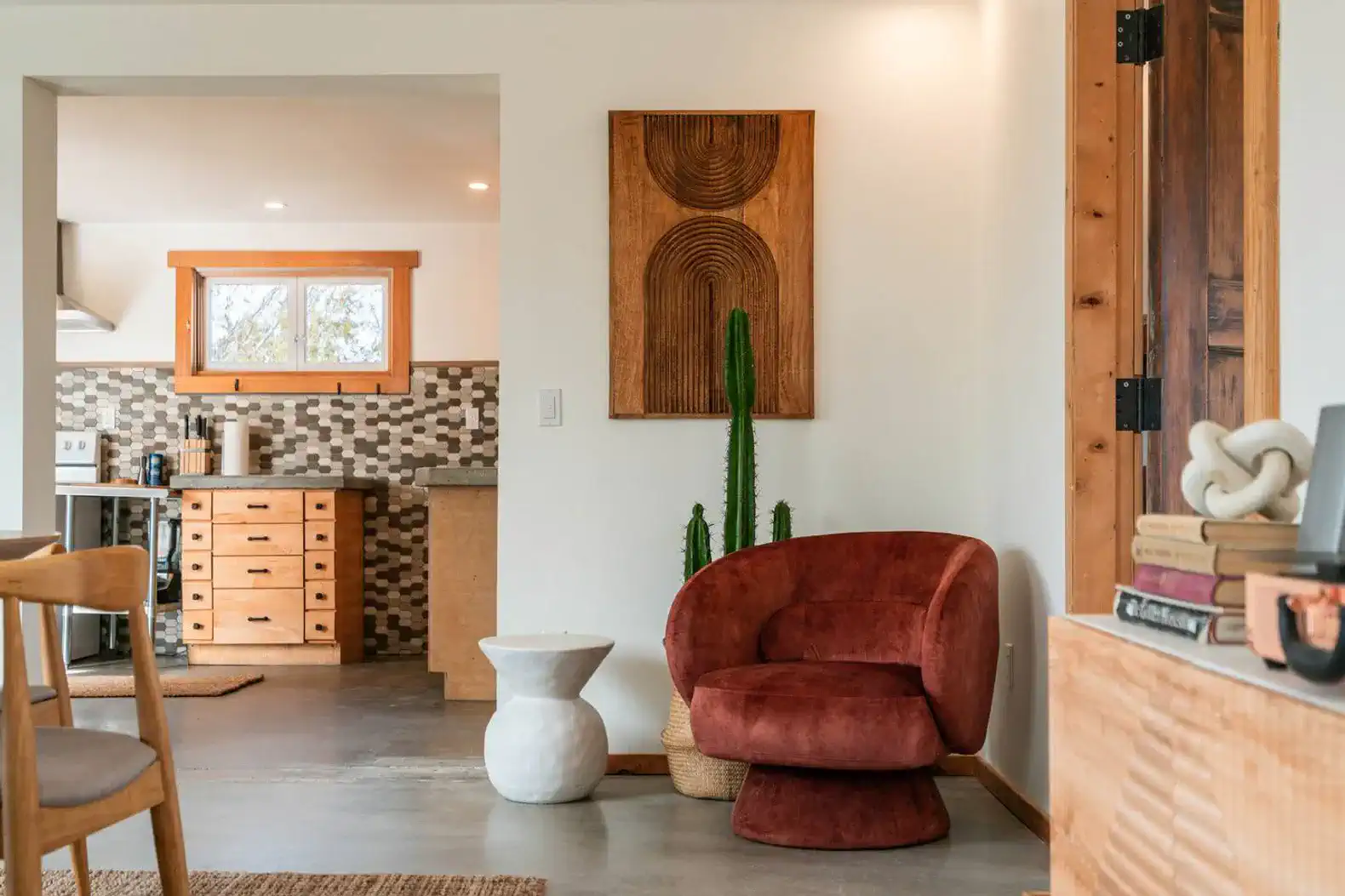 Cozy living area featuring a red chair, modern decor, and a view into the kitchen
