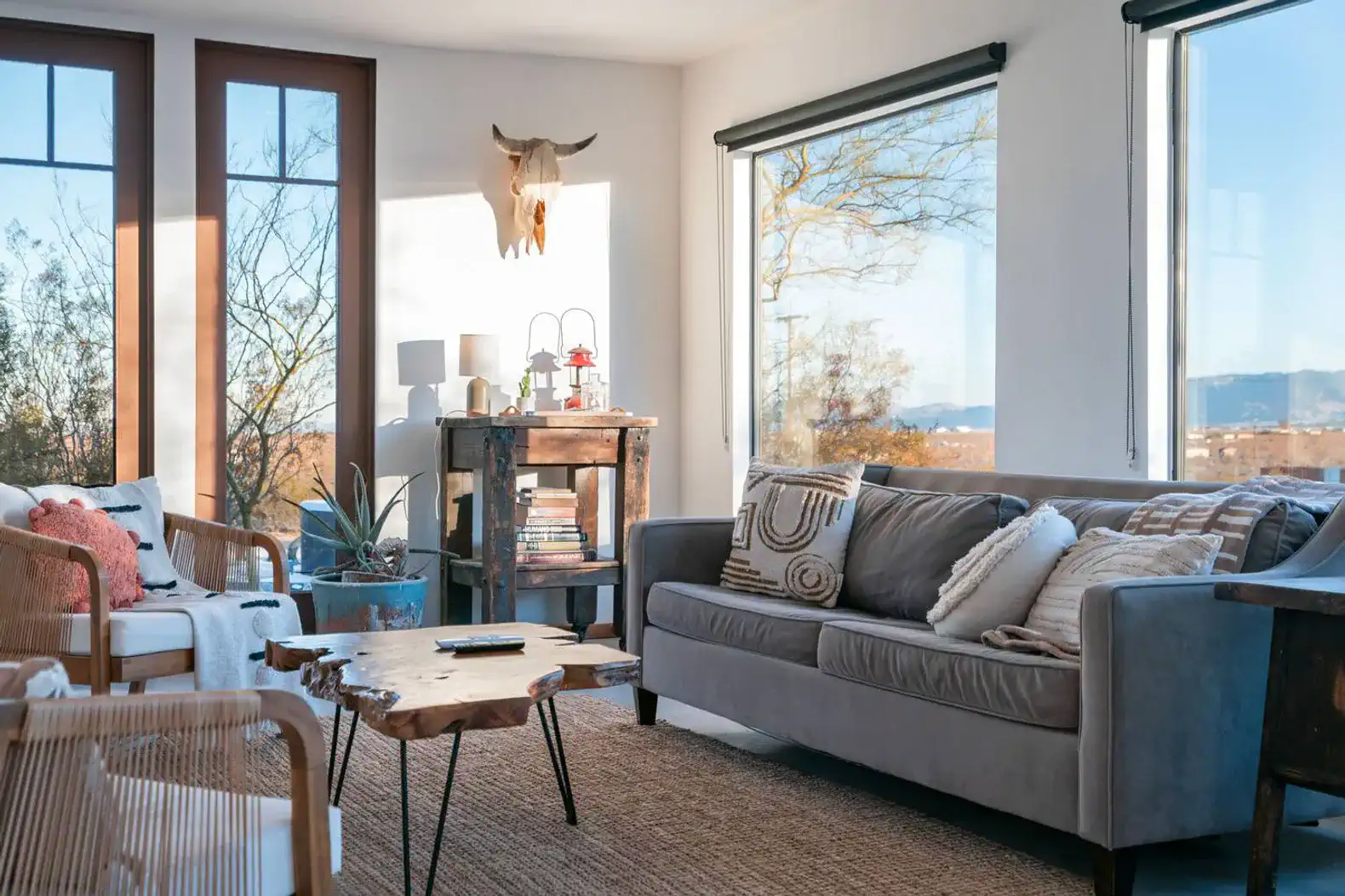 Cozy living room with large windows, modern furniture, and a rustic coffee table