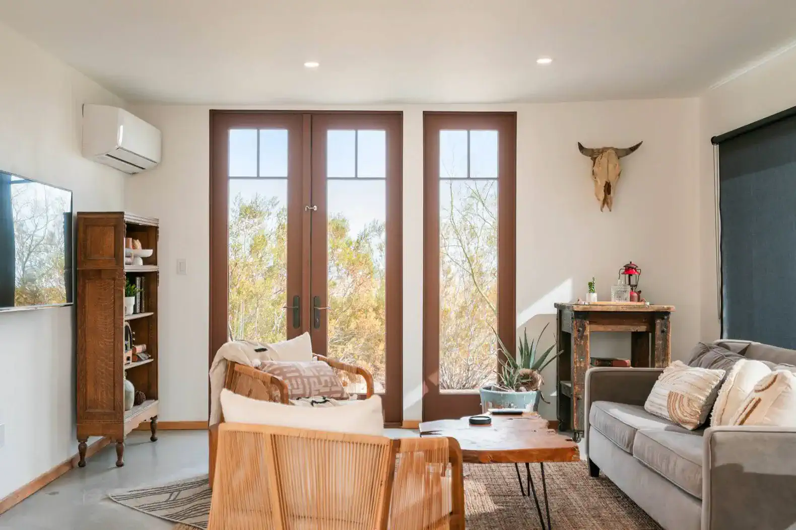 Cozy living room with large windows, rustic decor, and comfortable seating