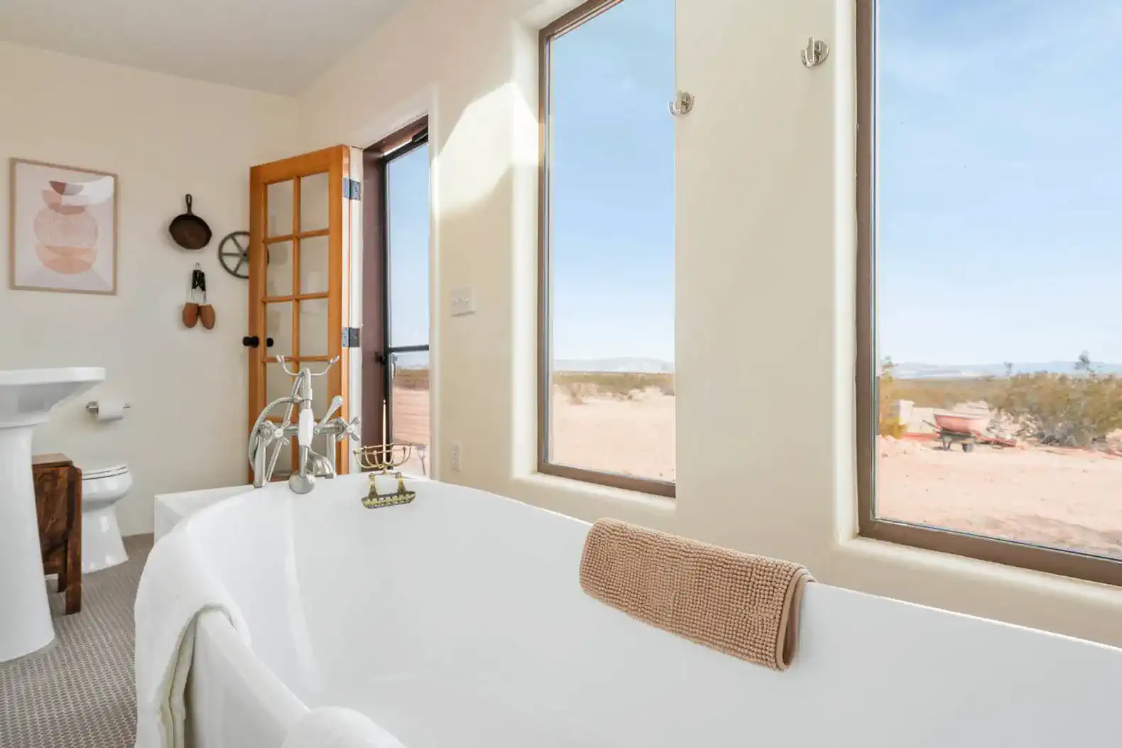 Bright bathroom featuring a freestanding tub with desert views through large windows