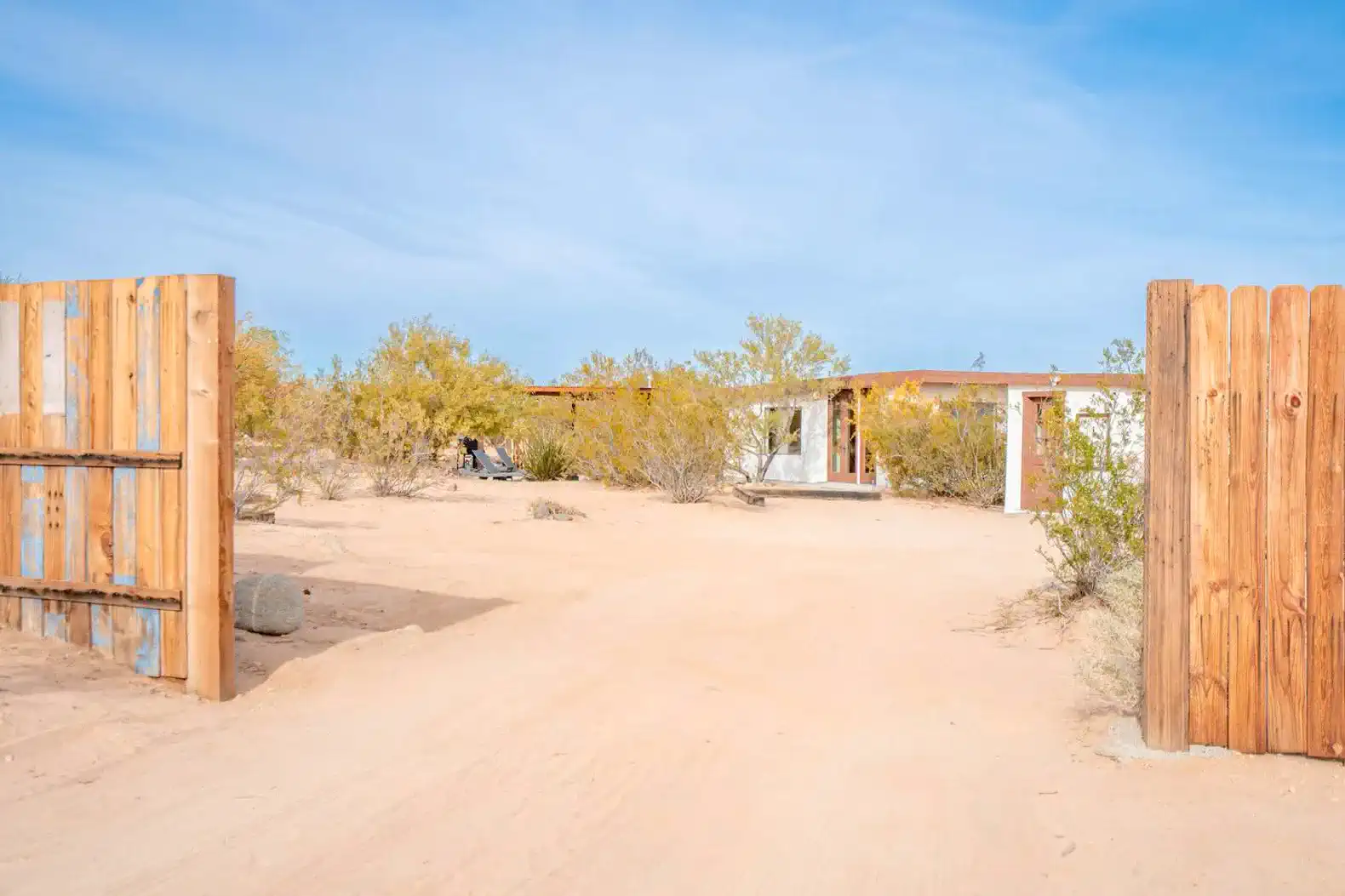 Entrance to a desert property with wooden gates and surrounding desert vegetation