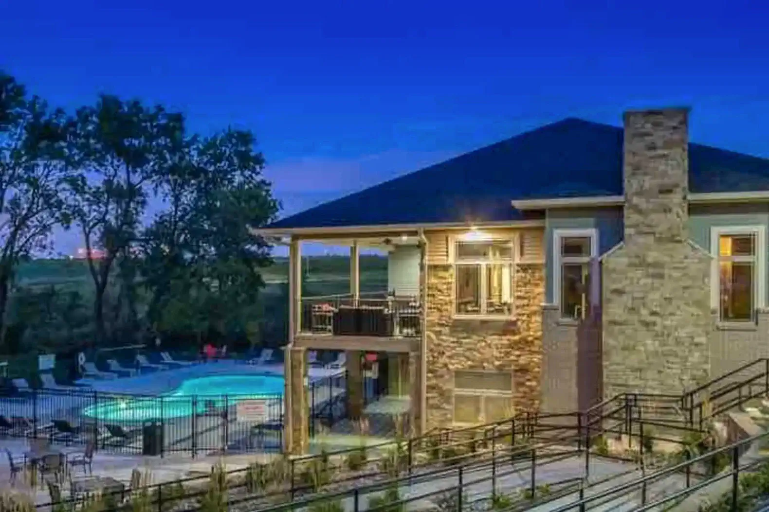 Resort-style clubhouse and outdoor pool, beautifully lit at night, with lounge seating and a peaceful, upscale atmosphere.