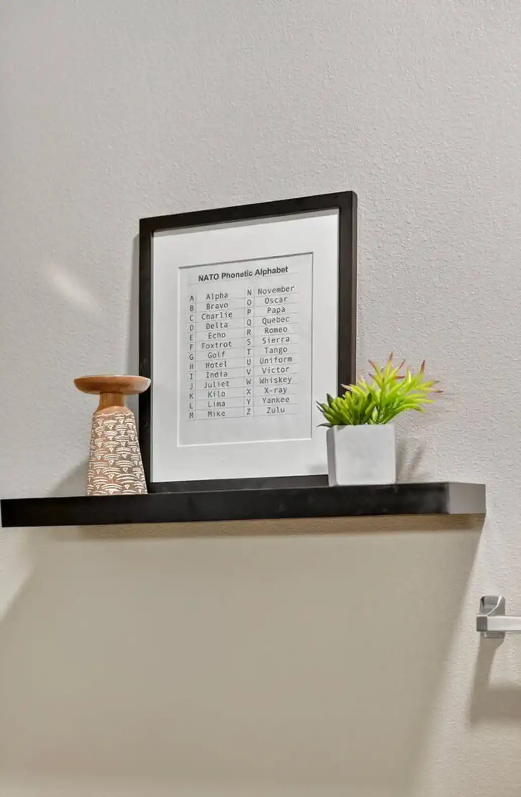 Unique wall shelf with framed décor and greenery. Small touches like this add charm and character to the modern design.