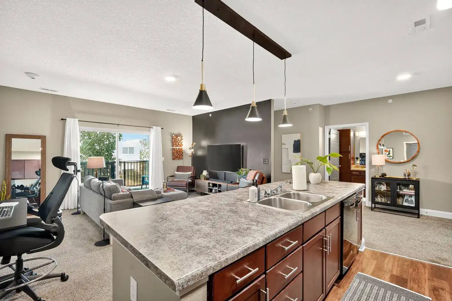 This open kitchen blends seamlessly with the living space, boasting rich cabinetry, sleek black appliances, and updated lighting.