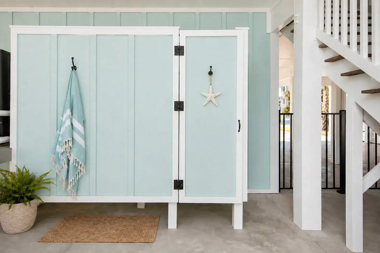 Outdoor storage area with beach-themed decor and a staircase nearby