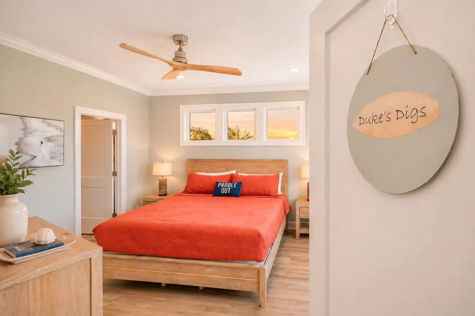 Cozy master bedroom with a red bedspread and sunset views through windows