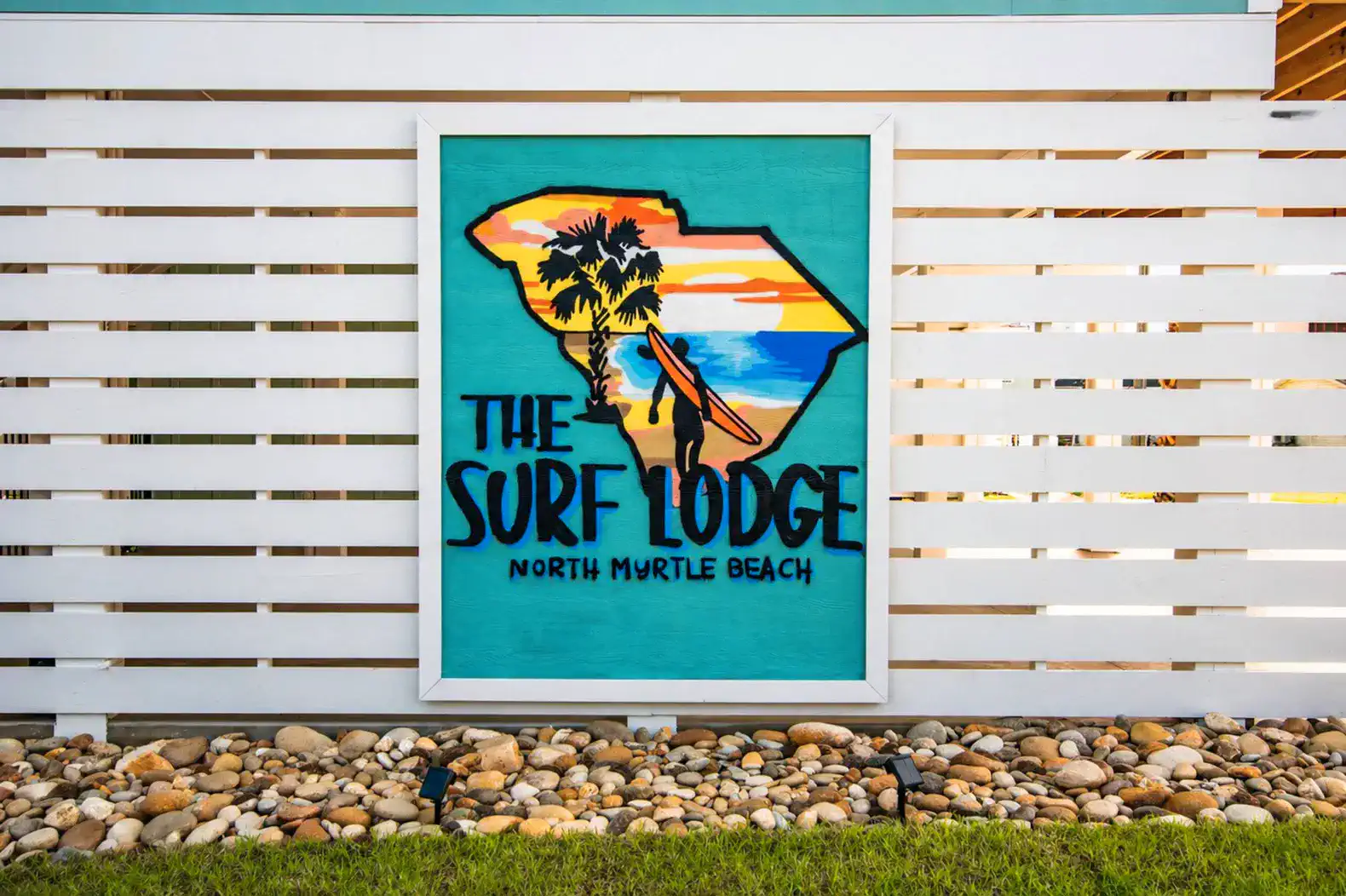 Colorful sign for The Surf Lodge featuring palm trees and beach scenery