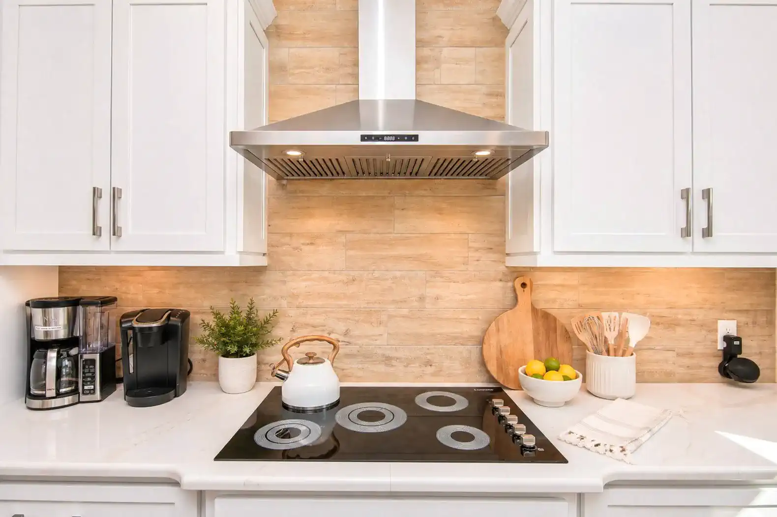 Modern kitchen with white cabinets, stovetop, and coffee maker