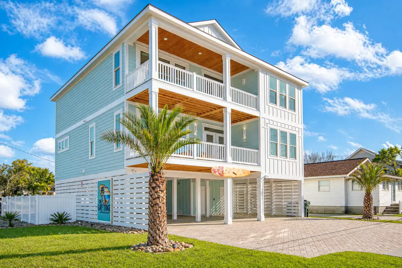 Modern beach house with multiple balconies and palm trees in front