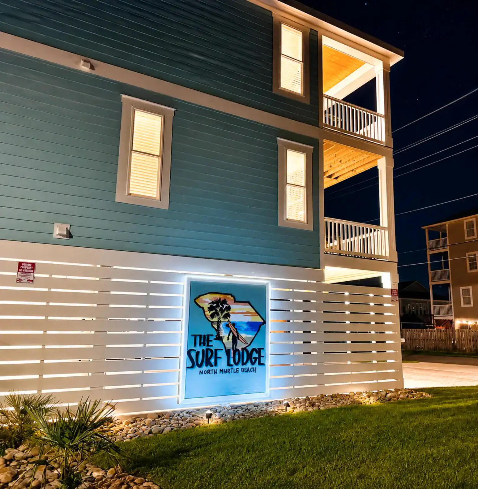 Exterior view of The Surf Lodge with illuminated sign and landscaping at night