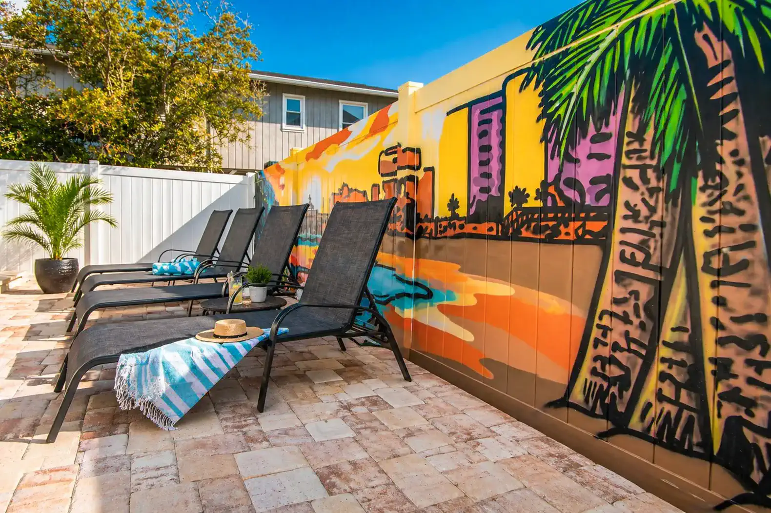 Colorful mural with palm trees and lounge chairs by a pool area