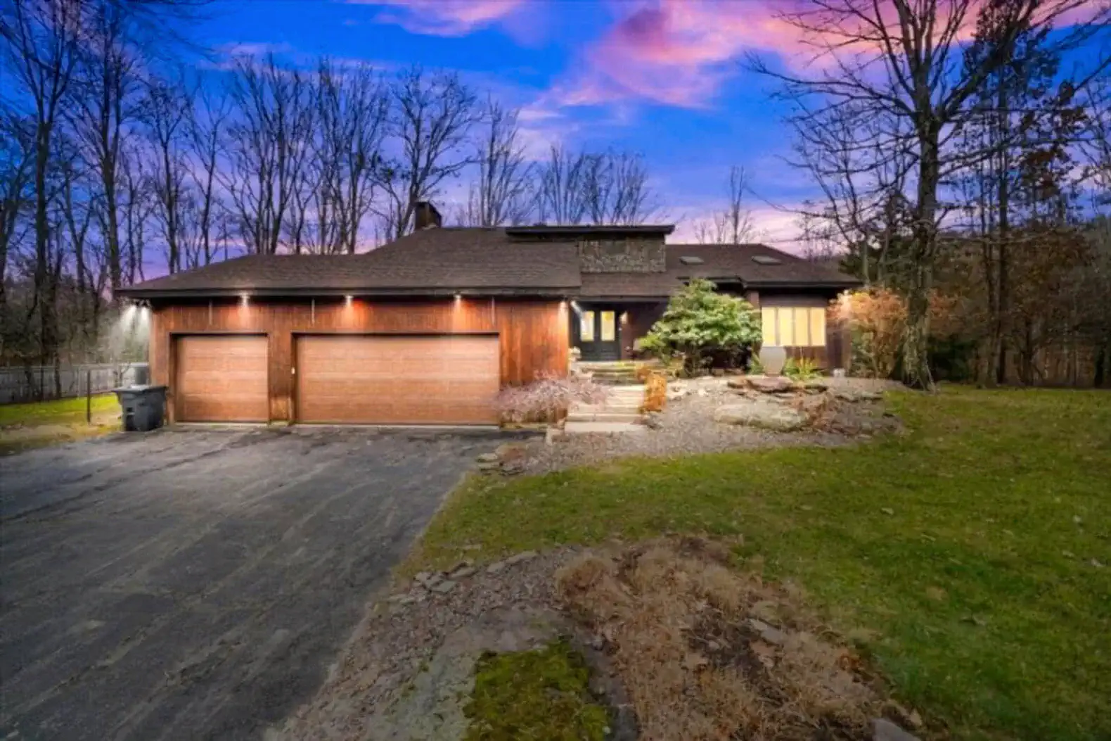 Modern mountain-style exterior with elegant lighting and a spacious driveway