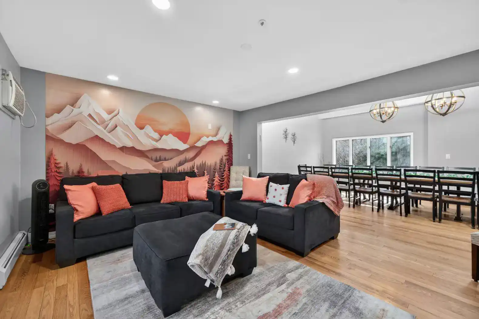 Open-concept lounge with mountain mural and a long dining table for a crowd