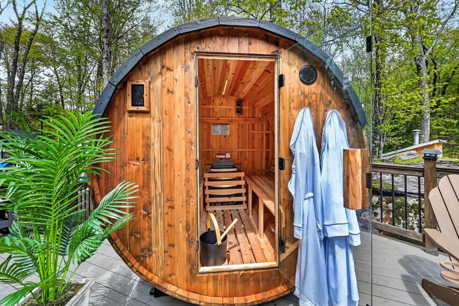 Wooden sauna with a round design, located outdoors surrounded by greenery