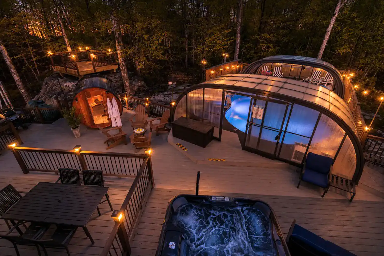 Outdoor area featuring a hot tub, indoor pool, and cozy seating with string lights