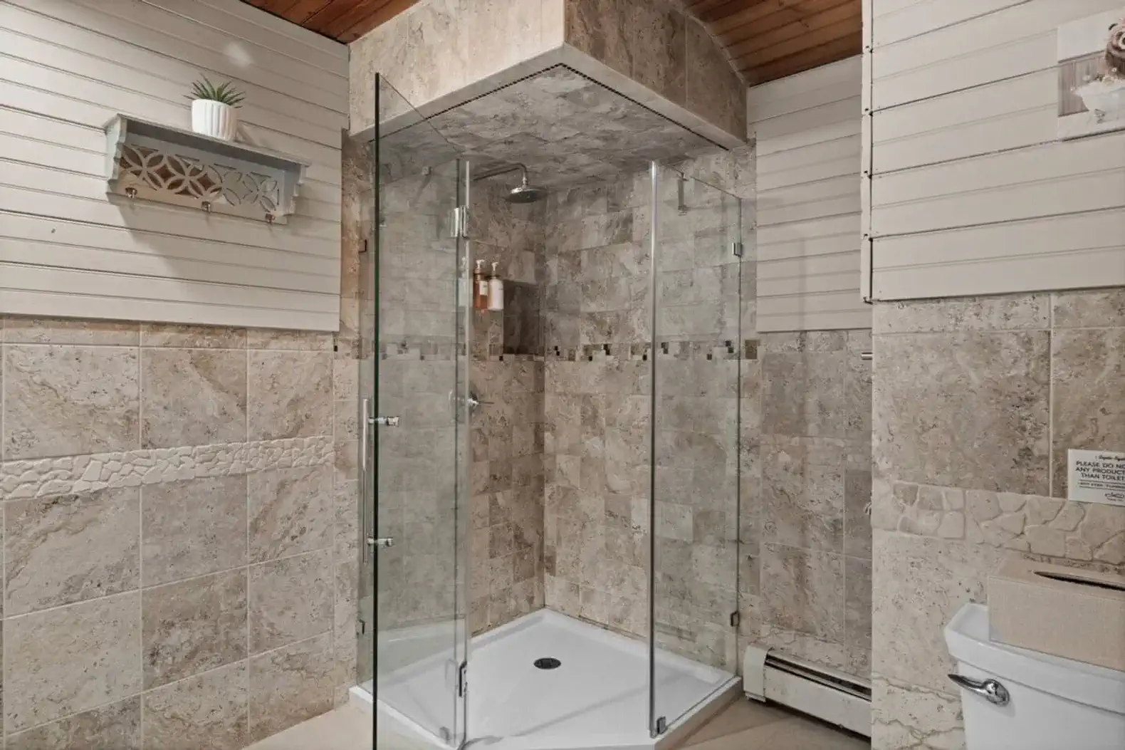 Walk-in glass shower, and elegant stone tile finishes.