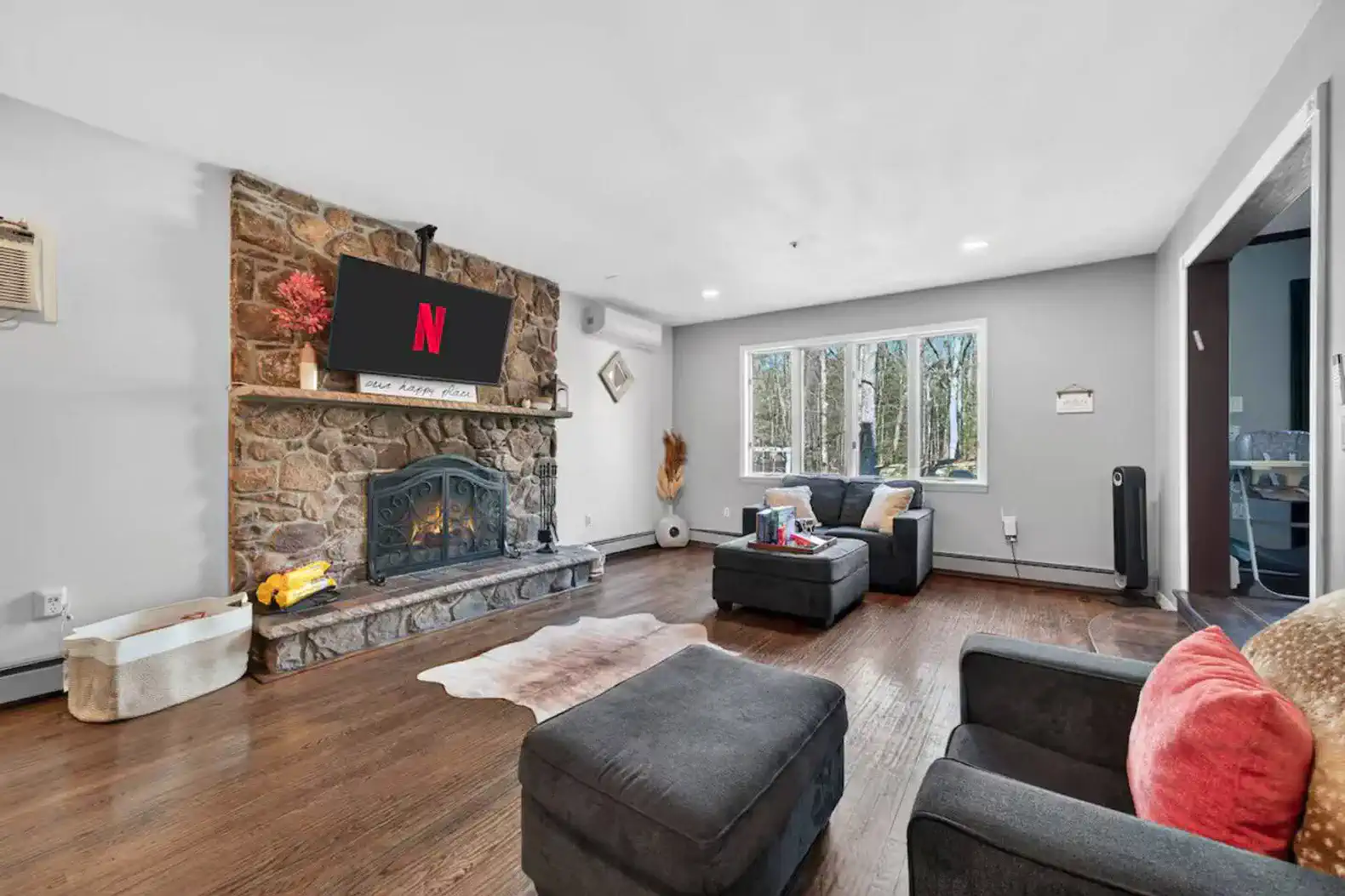 Cozy living room with stone fireplace and large windows overlooking nature