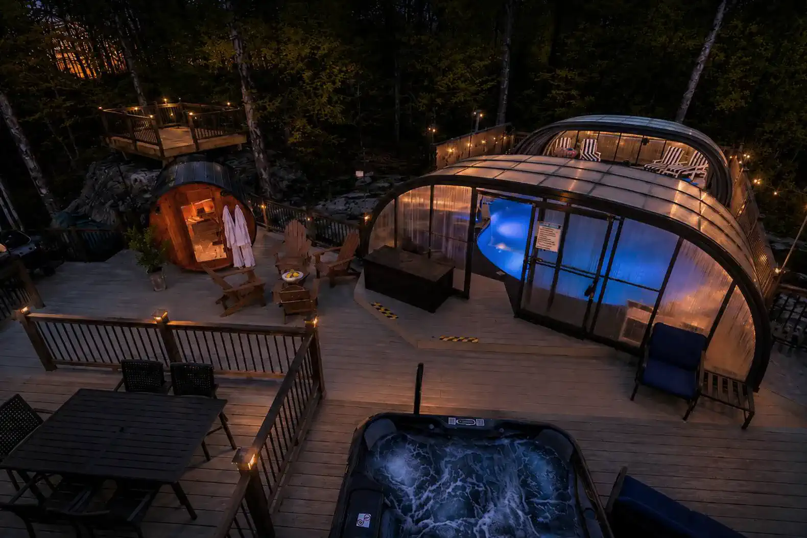 Outdoor area featuring a hot tub, indoor pool, and seating with ambient lighting