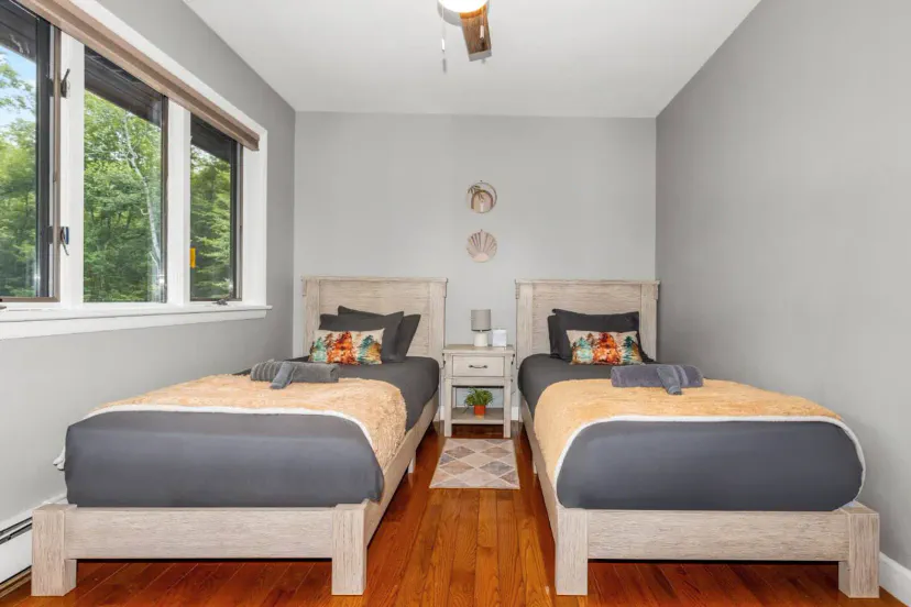 Cozy guest bedroom with two twin beds and natural light from large windows
