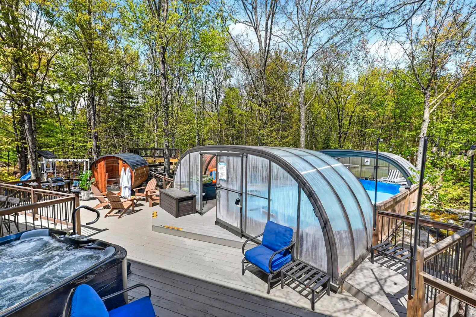 Outdoor area featuring a covered pool, hot tub, and seating surrounded by trees
