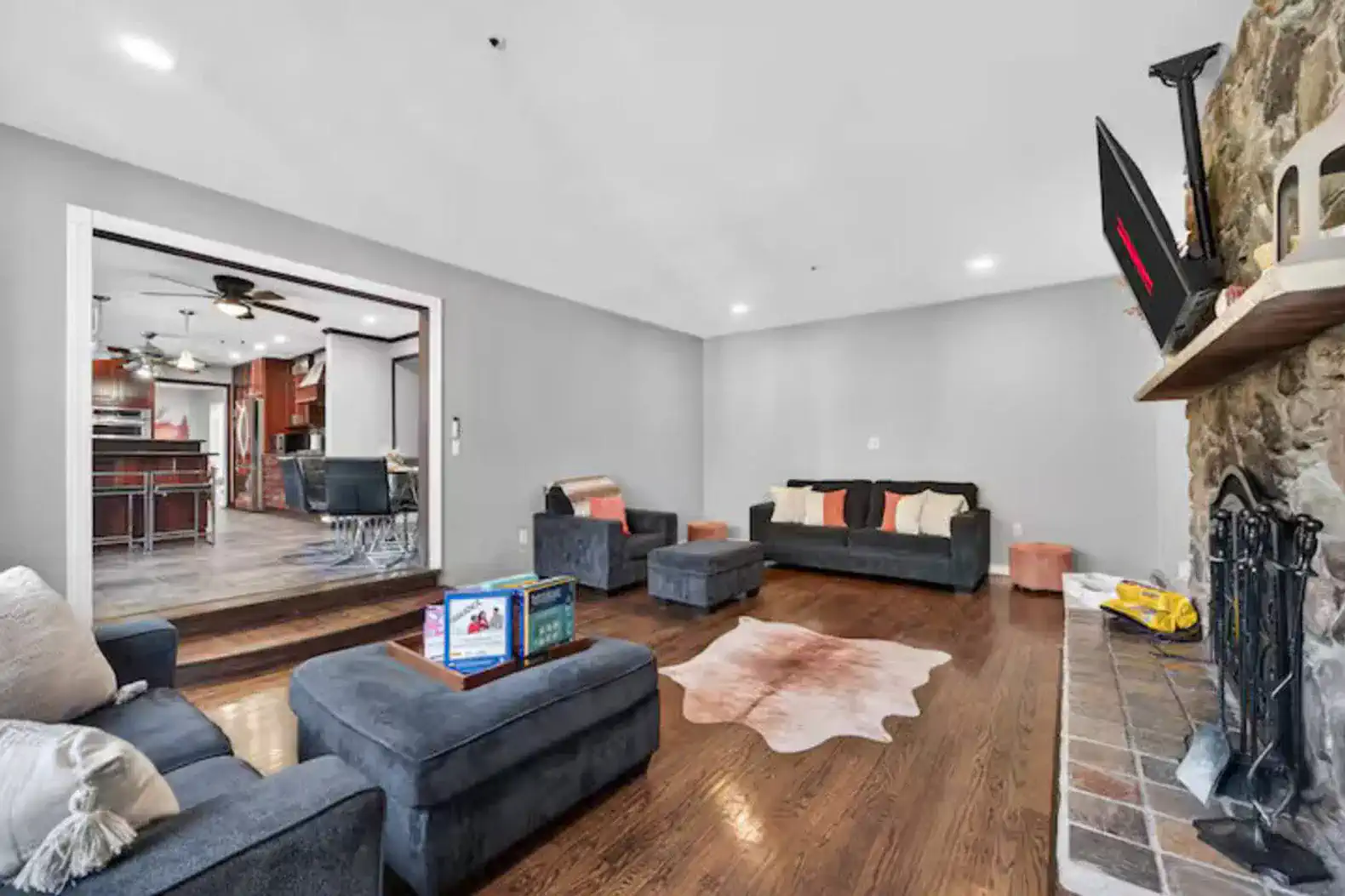 Spacious lounge with stone fireplace, TV, and open kitchen access