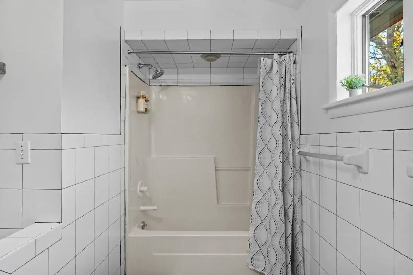 Bright and functional full bathroom featuring a bathtub and shower combo, spacious vanity, and modern tile finishes. Perfect for families or guests who prefer a relaxing soak after a day of exploring.