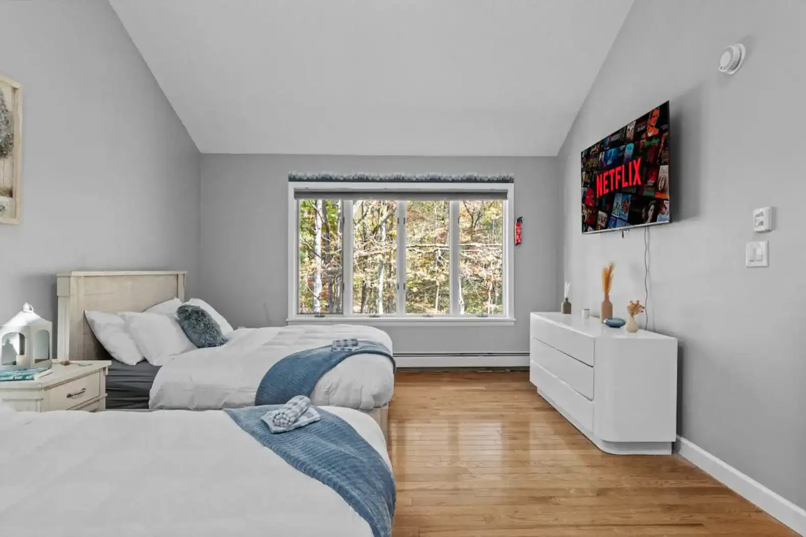 Bright and airy bedroom with two plush full beds, vaulted ceilings, and a large window overlooking the trees. Includes a smart TV with streaming access for cozy movie nights.
