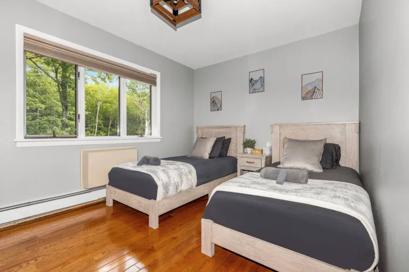 Cozy guest bedroom with two twin beds and large window overlooking greenery