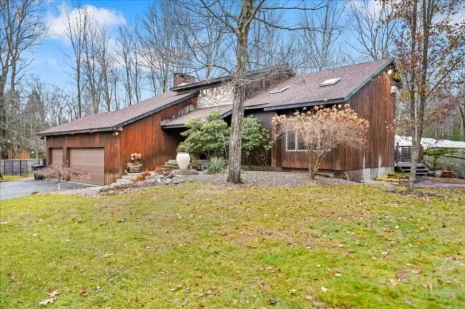 Rustic‑modern retreat with skylights, 2‑car garage, and lush lawn