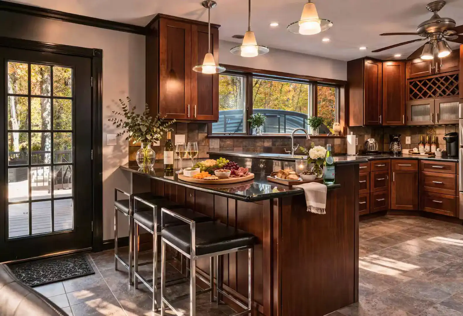 Modern full kitchen featuring rich wood cabinetry, stainless steel appliances, granite countertops, and a breakfast bar. Fully equipped for home-cooked meals with direct access to the outdoor deck for easy dining.