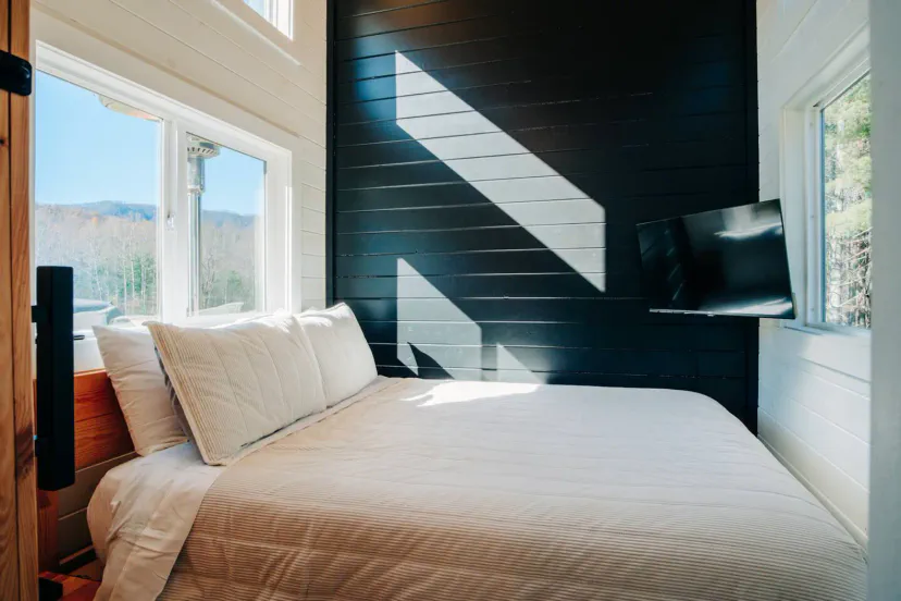 Cozy bedroom with large windows and a mounted TV