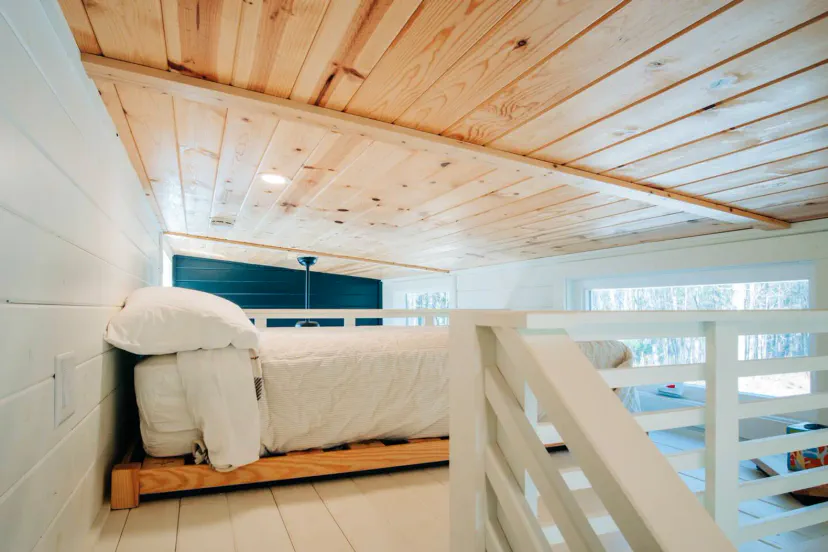 Cozy loft bedroom with wooden ceiling and natural light from windows