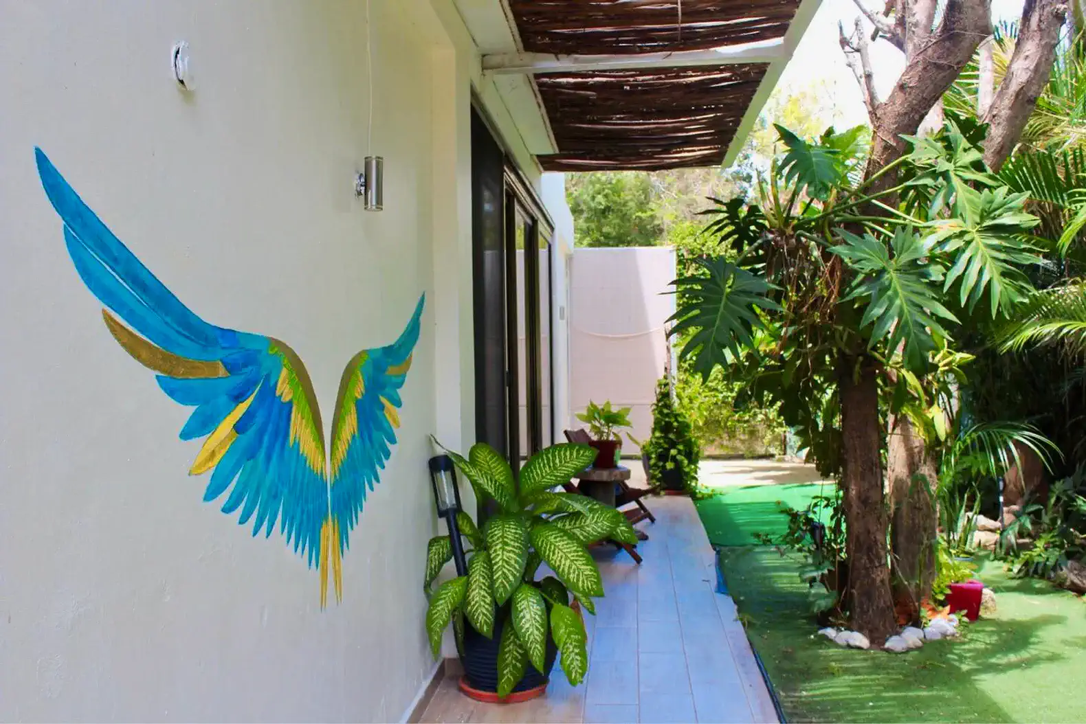 Terraza con mural de alas de ave y plantas tropicales