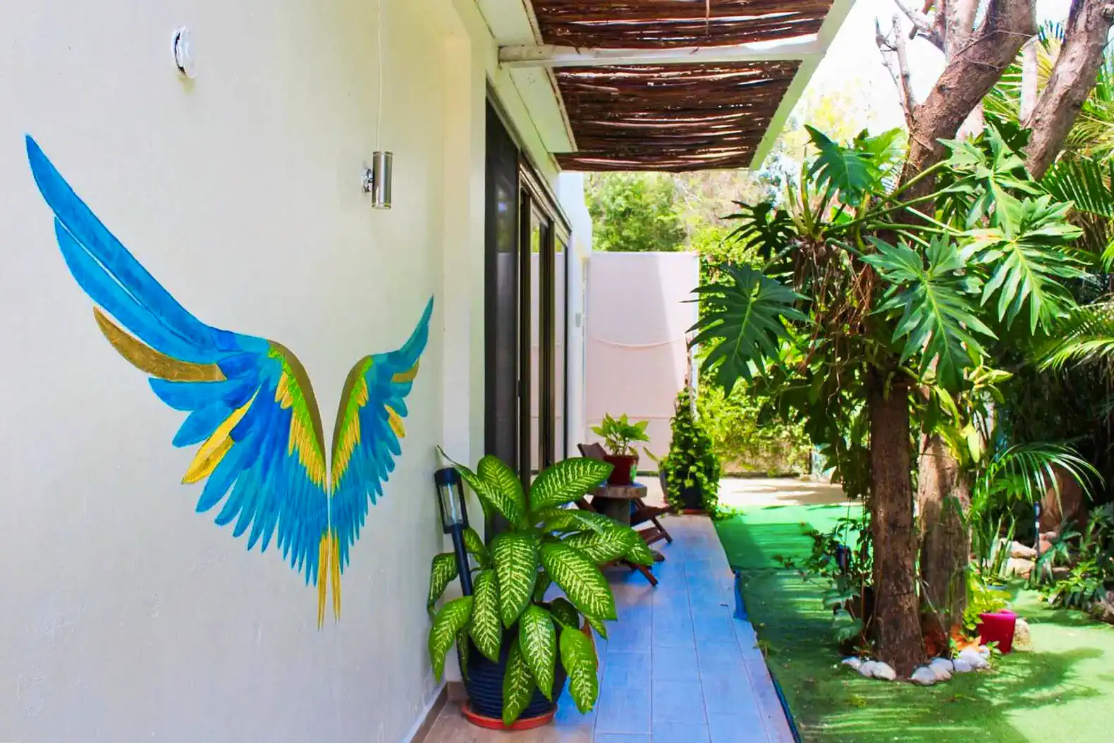 Terraza con mural de alas de pájaro y plantas verdes