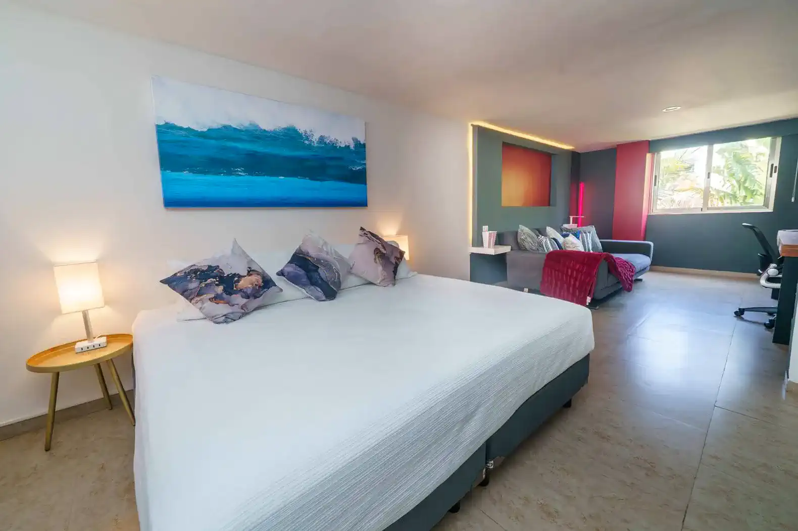 Habitación con cama grande, decoración moderna y sofá en un ambiente luminoso