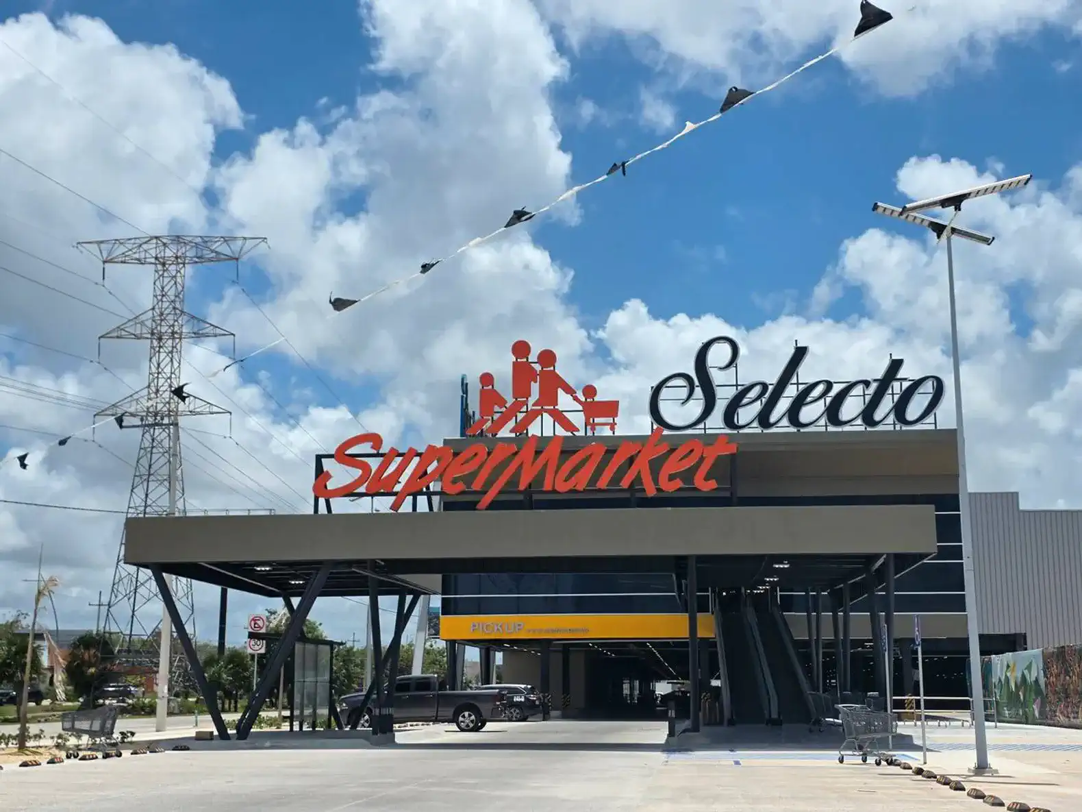 Fachada moderna del supermercado Selecto con un cielo azul y nubes