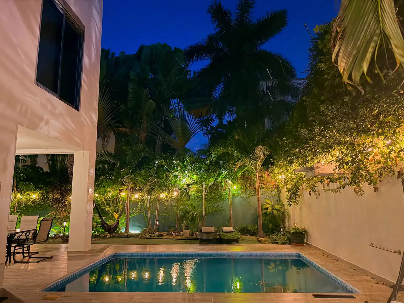 Private heated pool surrounded by lush greenery and ambient lighting at night