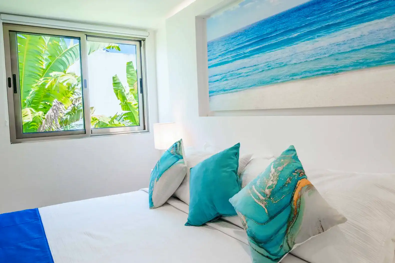 Habitación luminosa con cama y decoración en tonos azules y verdes